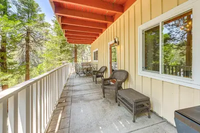 a porch with chairs and tables on a house at Game Room and 2 Decks Walkable Lake Arrowhead Cabin in Lake Arrowhead