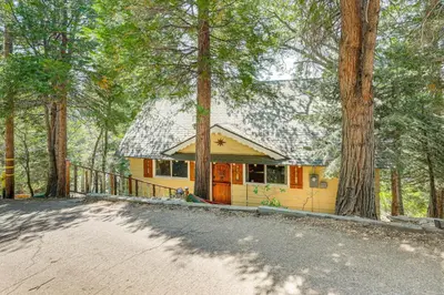 a yellow house in the middle of a forest at Game Room and 2 Decks Walkable Lake Arrowhead Cabin in Lake Arrowhead