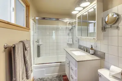 a bathroom with a tub and a sink and a mirror at Game Room and 2 Decks Walkable Lake Arrowhead Cabin in Lake Arrowhead