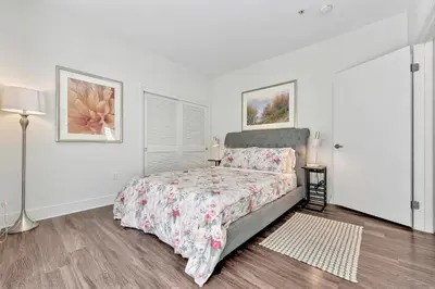 a white bedroom with a bed with a floral bedspread at 7 Large Down Town Santa Monica Apartment in Los Angeles