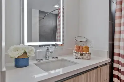 a bathroom sink with a mirror and a vase with flowers at 7 Large Down Town Santa Monica Apartment in Los Angeles