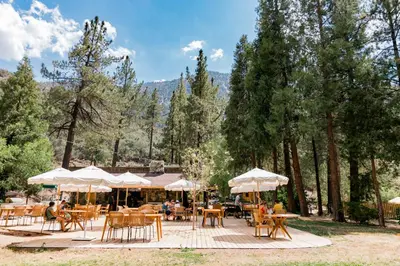 a patio with tables and chairs and umbrellas at Huttopia Paradise Springs in Valyermo