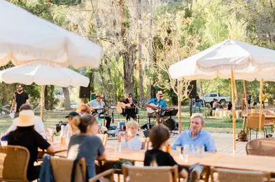 a group of people sitting at tables in a park at Huttopia Paradise Springs in Valyermo
