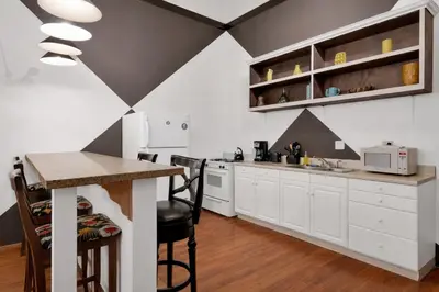 a kitchen with white cabinets and a table with chairs at St. Vincent Lofts in Los Angeles