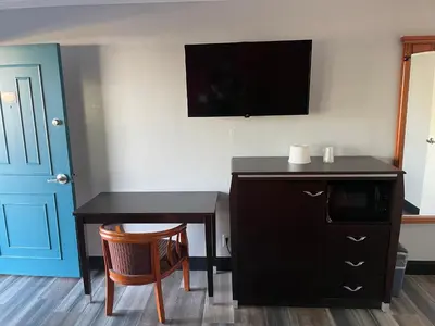 a room with a desk and a cabinet and a tv at La Casa Motel, Garden Grove - Anaheim in Garden Grove
