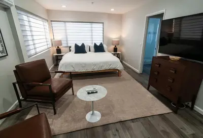 a bedroom with a bed and a chair and a tv at 50 M to Sand LGB 2 King Suites in Long Beach