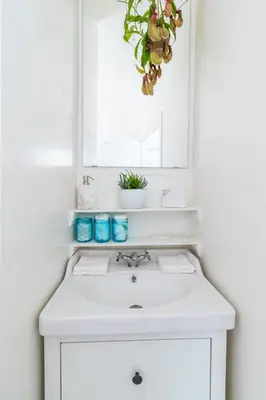 a white bathroom with a sink and a mirror at Sunny Boho Chic West Hollywood Flat! in Los Angeles