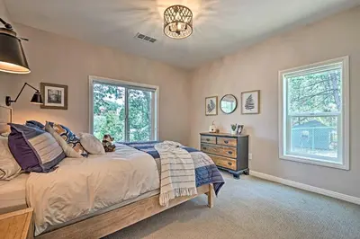 a bedroom with a bed and a dresser and windows at Luxe Lake Arrowhead Farmhouse with Deck and Patio in Lake Arrowhead