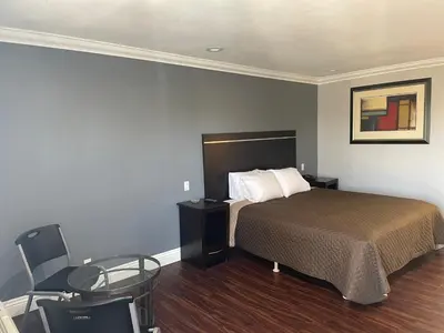 a bedroom with a bed and a table and a chair at Legacy inn & suites in Anaheim