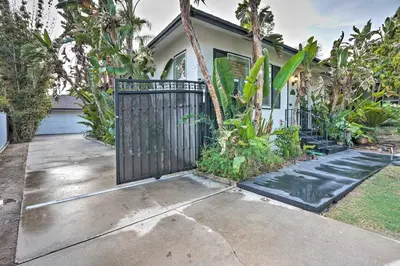a house with a gate in front of a driveway at Bakersfield Oasis Sweet Tropical Pool Setup! in Bakersfield