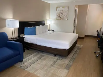 a bedroom with a large bed and a blue couch at Stanford Inn & Suites Anaheim in Anaheim