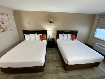 a hotel room with two beds and a mirror at Stanford Inn & Suites Anaheim in Anaheim