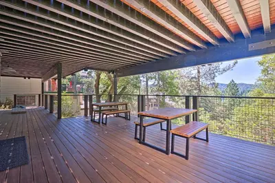 a wooden deck with benches and tables on it at Airy Alpine Getaway with Lake Arrowhead Views! in Lake Arrowhead