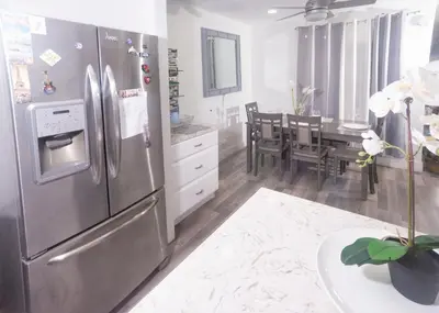 a kitchen with a stainless steel refrigerator and a dining room at Blanquitas Home in Long Beach