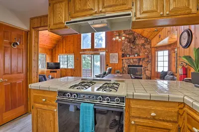a kitchen with wooden cabinets and a stove top oven at A-Frame Cali Cabin with Unobstructed Valley Views! in Running Springs
