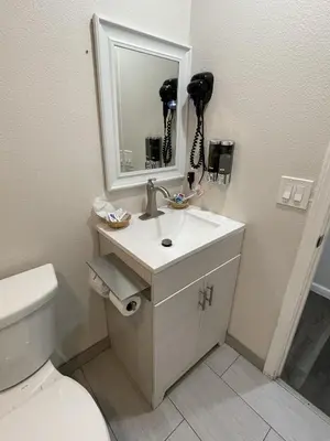a bathroom with a sink and a mirror and a toilet at Fontana Inn in Fontana