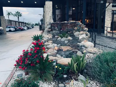 a garden with flowers and rocks in front of a building at Country Inn & Suites by Radisson, Bakersfield, CA in Bakersfield
