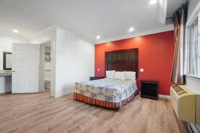 a bedroom with a bed with an orange wall at Santa Fe Inn Los Angeles in Huntington Park
