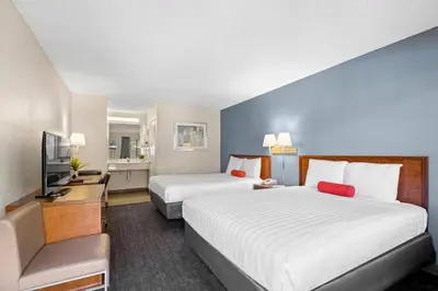 a hotel room with two beds and a flat screen tv at Good Nite Inn Calabasas in Calabasas