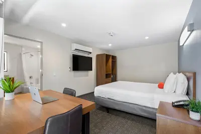 a hotel room with a bed and a desk with a laptop at Good Nite Inn Calabasas in Calabasas