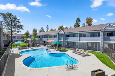 a pool with chairs and umbrellas in front of a building at Good Nite Inn Calabasas in Calabasas