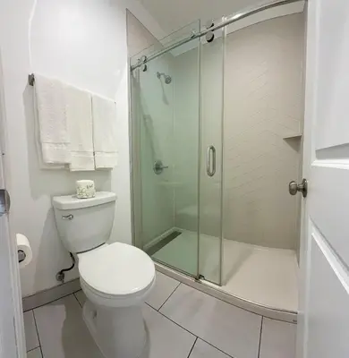 a bathroom with a toilet and a glass shower at La Casa Motel, Los Angeles - Burbank Airport in Sun Valley