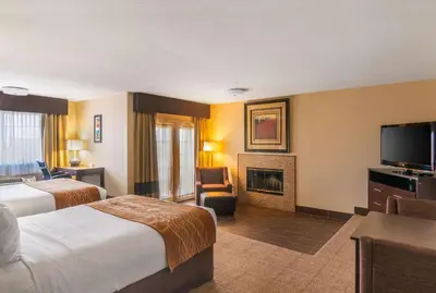 a hotel room with two beds and a fireplace at Comfort Inn & Suites Mojave in Mojave