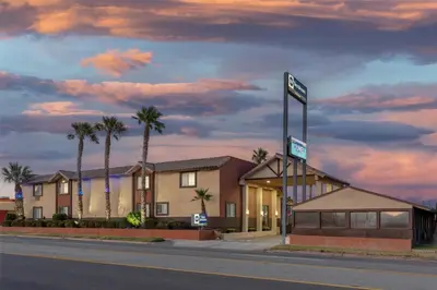 a hotel on the side of a street with palm trees at Best Western Desert Winds in Mojave