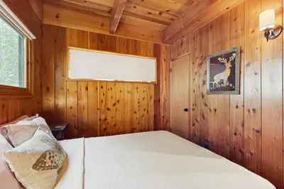 a bedroom with a bed in a wood paneled room at Wooded Comfort in Lake Arrowhead