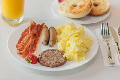 a plate of breakfast food with eggs sausage and bacon at Comfort Inn & Suites Ventura Beach in Ventura