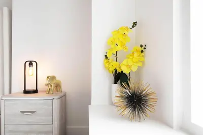 a vase filled with yellow flowers sitting next to a dresser at Sky-Rise Apartments in Los Angeles