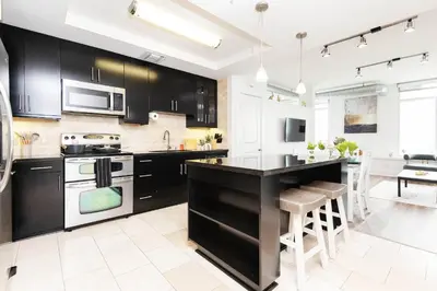 a kitchen with black cabinets and a kitchen island at Sky-Rise Apartments in Los Angeles