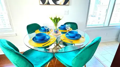 a glass table with green chairs and a dining room at Sky-Rise Apartments in Los Angeles