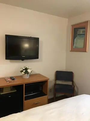 a hotel room with a bed and a desk with a television at OceanView Motel in Huntington Beach
