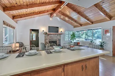 an open kitchen and living room with a fireplace at Modern and Unique Cabin with Deck by Lake Gregory! in Crestline