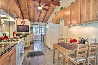 a kitchen with a table and a refrigerator at 1 Mi to Lake Gregory Boho Crestline Cabin in Crestline