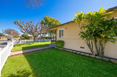 a house with a green yard next to a white fence at Disney Getaway in Anaheim