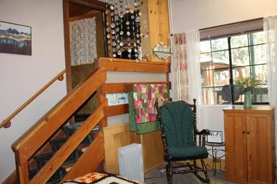 a room with a staircase with a chair and a window at The Old Bear BnB in Pine Mountain Club