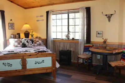 a bedroom with a bed and a table and a window at The Old Bear BnB in Pine Mountain Club