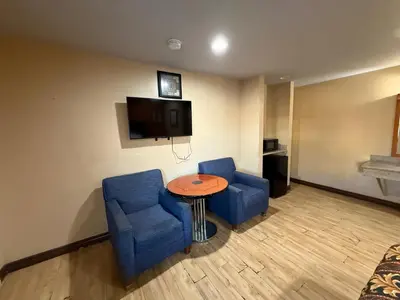 a room with two blue chairs and a table and a tv at Rocky Inn Motel Long Beach, CA in Long Beach
