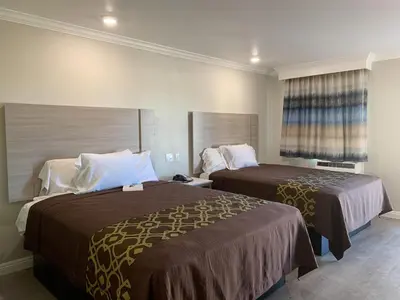 a hotel room with two beds and a window at Mojave Inn in Victorville