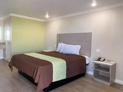 a bedroom with a bed and a table with a phone at Mojave Inn in Victorville