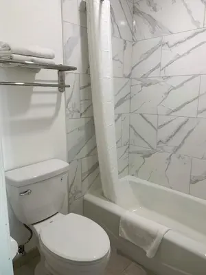 a white bathroom with a toilet and a shower at Mojave Inn in Victorville