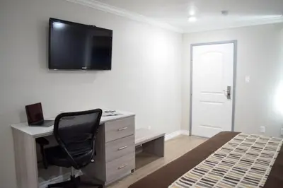 a bedroom with a desk with a computer and a chair at Mojave Inn in Victorville