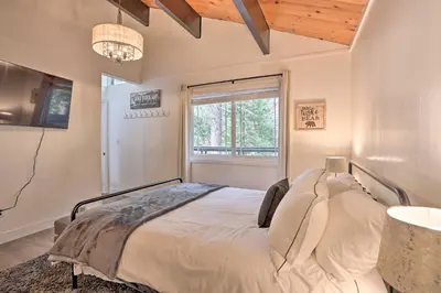a bedroom with a large bed with a window at Modern Cabin with Game Room and Deck, Near Skiing in Running Springs