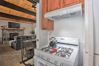 a kitchen with a stove and a living room at Modern Cabin with Game Room and Deck, Near Skiing in Running Springs