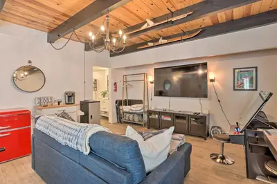 a living room with a blue couch and a flat screen tv at Modern Cabin with Game Room and Deck, Near Skiing in Running Springs