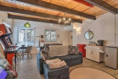 a living room with a couch and a table and a kitchen at Modern Cabin with Game Room and Deck, Near Skiing in Running Springs
