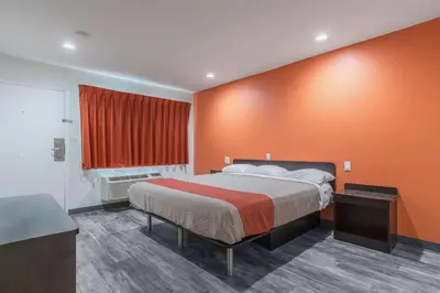 a bedroom with a bed with an orange wall at Motel 6-Barstow, CA - Route 66 in Barstow