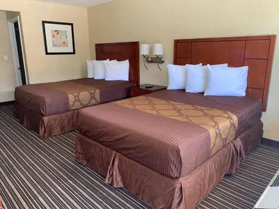 two beds in a hotel room with white pillows at Buena Park Inn in Anaheim